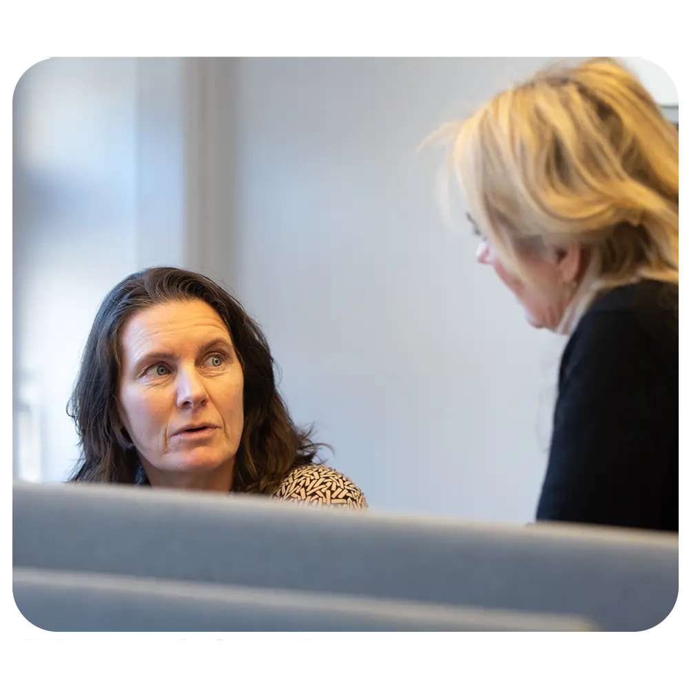 En kvinne diskuterer budsjettet med en annen kvinne på et kontor.