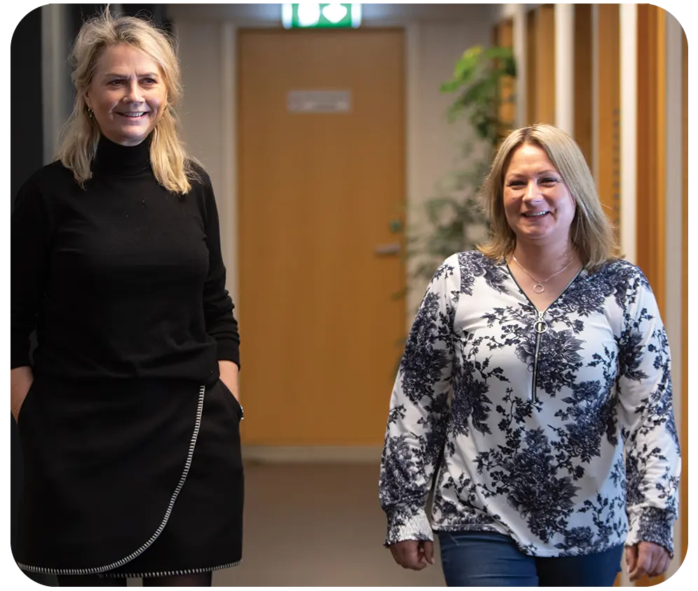 To kvinner diskuterer lønn i en kontorgang.